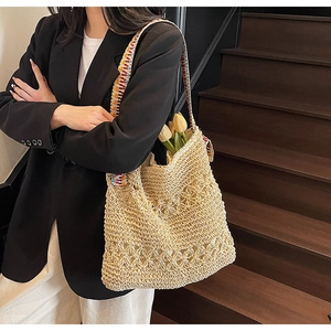 Close-up of handmade straw tote bag with ethnic print shoulder strap on a model