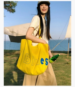 Gros plan d'un grand sac fourre-tout en toile jaune avec texte bleu à la plage