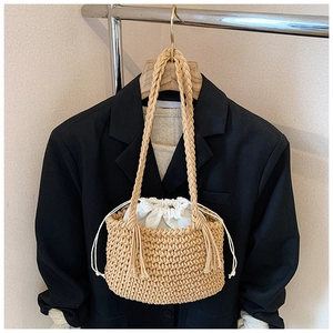 Detail of beige woven bucket bag featuring thick cord texture and white drawstring lining