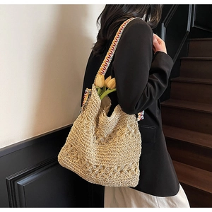 Detail of hollow-out hand-woven straw bag featuring a vibrant ethnic style wide strap