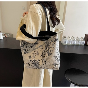 Detail of canvas tote bag showing bamboo ink print and wide black shoulder strap texture