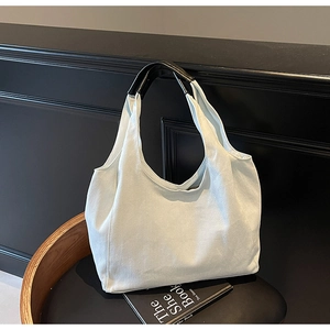 Dettaglio di una borsa tote in tela bianca con manici neri in un ambiente elegante
