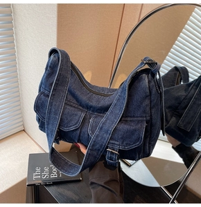 Macro shot of blue denim hobo bag featuring silver buckles and dual front flap pockets