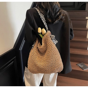 Detail of handmade straw shoulder bag with striped scarf and tulip on dark steps