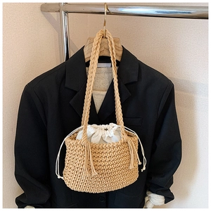 Detail of woven straw bucket bag with canvas drawstring liner and side tassels