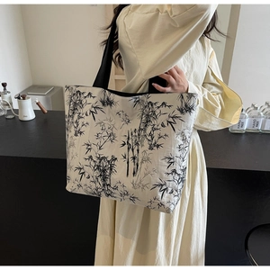 Close-up of a canvas tote bag with bamboo ink print on model in casual indoor setting