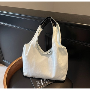 Dettaglio di una borsa tote in tela con manici in pelle nera su una sedia elegante