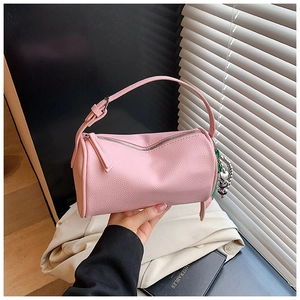 Detailed macro view of pink cylinder bag showing lychee leather texture and heart charm