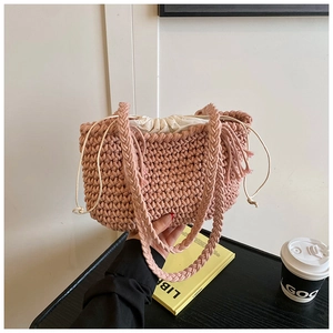 Detail of coral pink hand-woven bucket bag with fringe and white canvas drawstring liner
