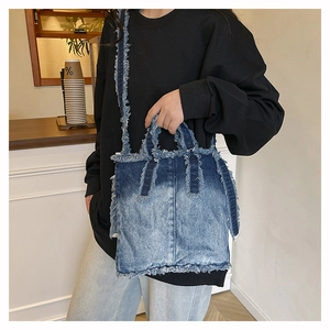Détail d'un sac cabas en jean dégradé bleu avec bords effilochés porté par un mannequin