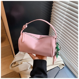 Detailed macro of pink lychee leather texture on a cylindrical pillow bag for women