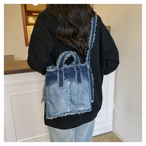 Détail des bords effilochés et du dégradé de jean bleu sur un sac cabas élégant