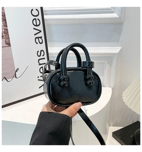 Detail of glossy black leather mini bag with round handles and sleek texture