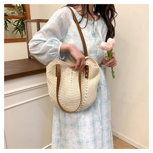 Detail of handwoven straw tote with brown leather handles and intricate crochet patterns