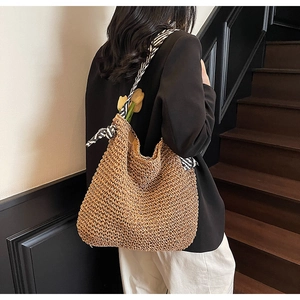 Detail of hand-woven straw tote with zebra print strap and ribbon bow on model