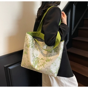 Close-up of canvas tote bag featuring green bamboo print and striped interior lining