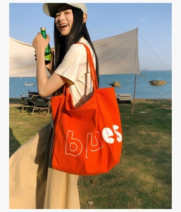 Gros plan du sac fourre-tout en toile orange vif avec inscription blues blanche à la plage