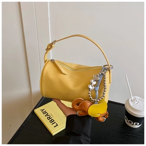 Detail of yellow pebbled leather barrel bag with cute elephant charm and beaded tassel