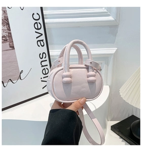 Detail of pink mini bowling bag featuring ball-joint handles and textured leather finish