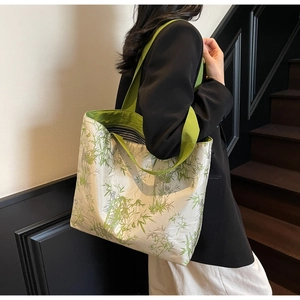 Detail of canvas tote bag with green bamboo print and striped lining on shoulder
