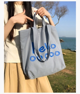 Detail van lichtblauwe canvas tas met artistieke hello-tekstprint in een zeedecor