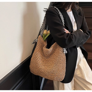 Detail of handmade straw shoulder bag featuring a chic black and white striped scarf strap