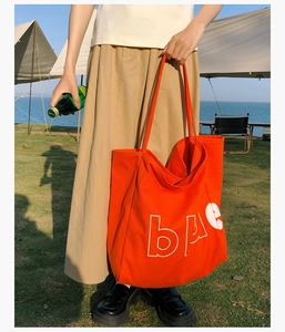 Vue détaillée d'un grand sac cabas en toile orange avec imprimé 'bae' en extérieur