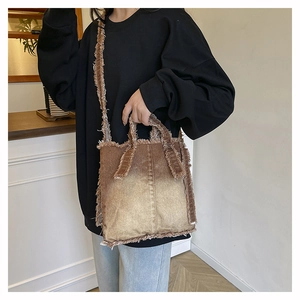 Détail du sac cabas en denim dégradé marron avec bords effilochés et bandoulières