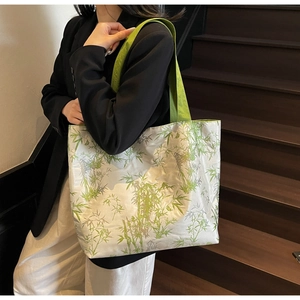 Detail of silver canvas tote with bamboo print and green strap on a model