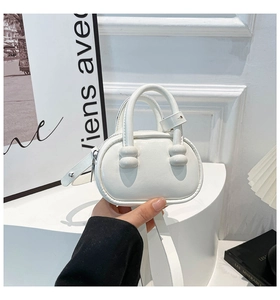 Close-up of a white mini semi-circle handbag with beaded handle details and shoulder strap