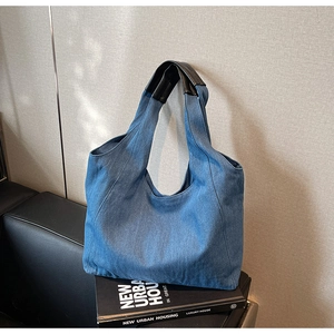 Dettaglio della borsa tote in denim blu con manici rivestiti in pelle nera di alta qualità