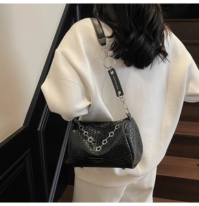 Close-up of black woven shoulder bag with floral metal chain and fashion leather tag