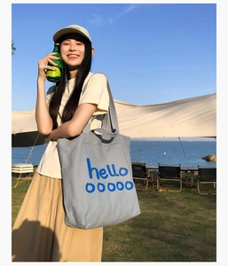 Buitenopname van een lichtblauwe canvas draagtas met artistieke hello belettering