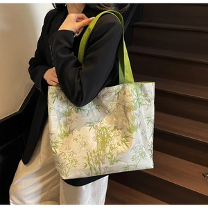 Close-up of green bamboo leaf print on silver canvas tote bag with vibrant green handles