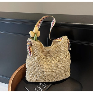 Detail of handmade hollow straw bag with floral texture and colorful ethnic shoulder strap