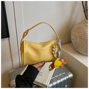 Detail of yellow lychee texture leather handbag with gold elephant and heart charms