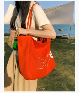 Gros plan d'un grand sac cabas en toile orange avec des lettres blanches imprimées