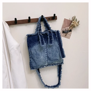 Détail du sac cabas en jean bleu avec bords effilochés et texture vintage
