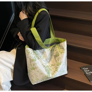 Detail of bamboo print canvas tote bag with green straps on a person's shoulder