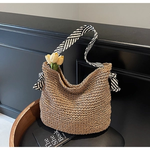 Detail of handmade straw shoulder bag with striped straps and tulip decoration