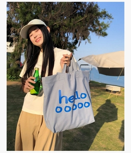 Lichtblauwe canvas draagtas met hello-opdruk in een zonnige buitenomgeving op de camping