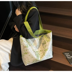 Close-up of white tote bag with green bamboo print and striped lining on wooden steps