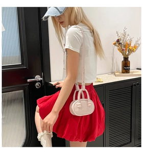 Model showing a mini pink leather bowling bag with top handles and adjustable strap