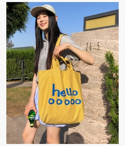 Buitenaanzicht van een grote gele canvas shopper met artistieke blauwe belettering