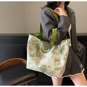 Detail of bamboo print canvas tote bag featuring green wide handles and fabric texture