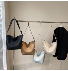 Détail de quatre sacs seaux en cuir grainé déclinés en noir, kaki, bleu ciel et blanc