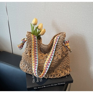 Close-up of bohemian straw bag featuring colorful geometric strap and bow detail