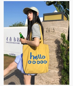 Streetstyle-weergave van een grote gele canvas tote bag met blauwe hello ooooo tekst