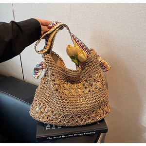 Detail view of handmade straw woven bag with bohemian colorful wide strap and tulip decor