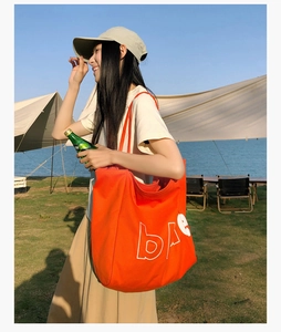 Détail d'un grand sac fourre-tout orange en toile avec inscription sur fond de lac